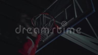 泛光篮球场篮球比赛中职业篮球运动员扣篮的特写图像。